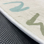 Load image into Gallery viewer, Close-up of the sticky dots for additional safety found the underside of a children's round carpet with colorful letters of the alphabet arranged in a circular pattern
