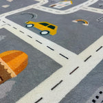 Load image into Gallery viewer, Close up of a car and road illustrations on a children's round carpet depicting a small town design
